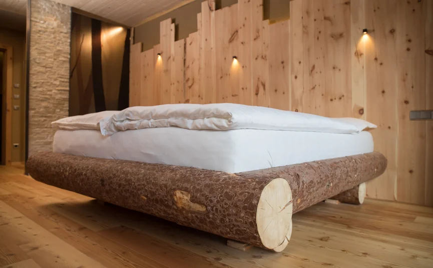 Wooden log bed with white bedding in a wooden room