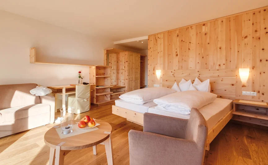 Bright wooden bedroom with double bed and cozy seating area