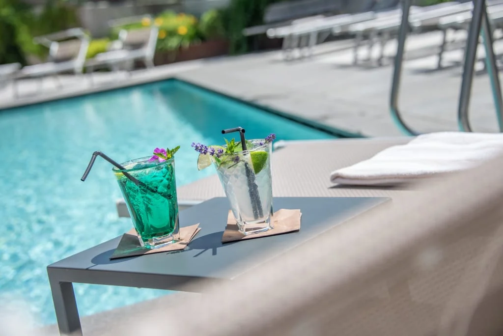 Two colorful cocktails on a table by the pool