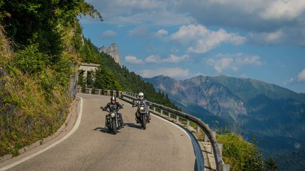 Friaul – Karnien © Moppetfoto.de Zwei Motorradfahrer auf kurviger Bergstraße mit Bergen im Hintergrund.
