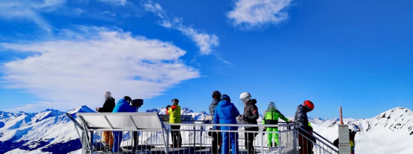 Schneekristallwochen Uitkijkplatform met skiërs bij besneeuwde bergen en blauwe lucht