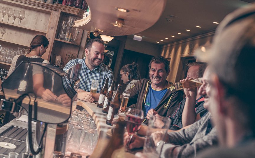 Menschen sitzen lachend und trinkend an einer Bar