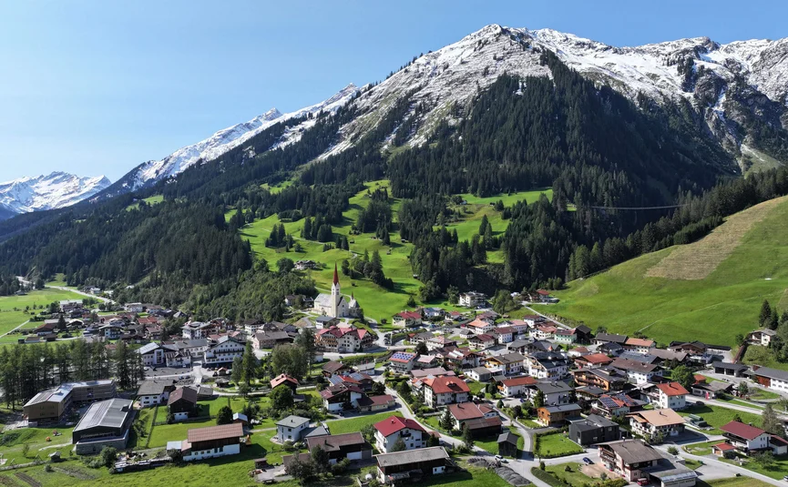 Village below snow-capped mountains on a clear day