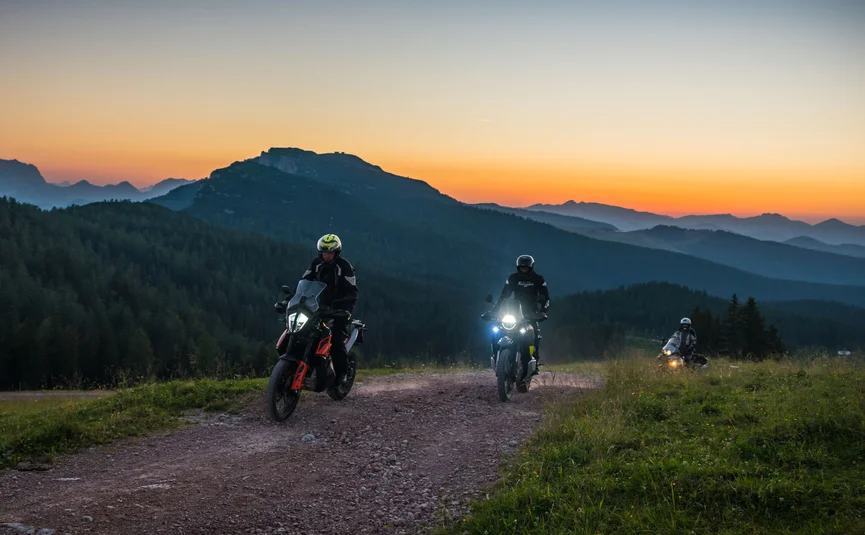Motorvakantie in SalzburgerLand © Moppetfoto.de Drie motorfietsers op een bergpad bij zonsondergang