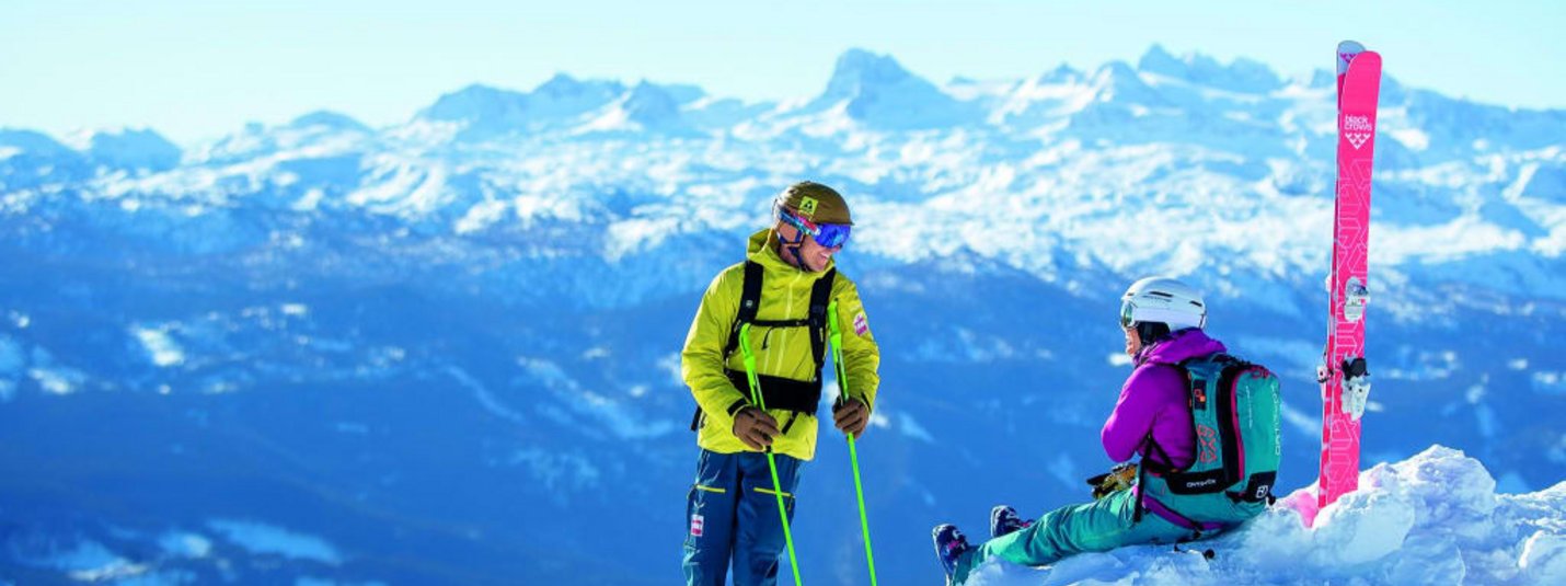 Mid-Week-Skitage 5 Zwei Skifahrer in bunter Kleidung auf schneebedecktem Berg mit Bergpanorama