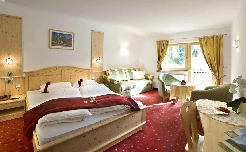 Cozy hotel room with wooden furniture, double bed, and seating area