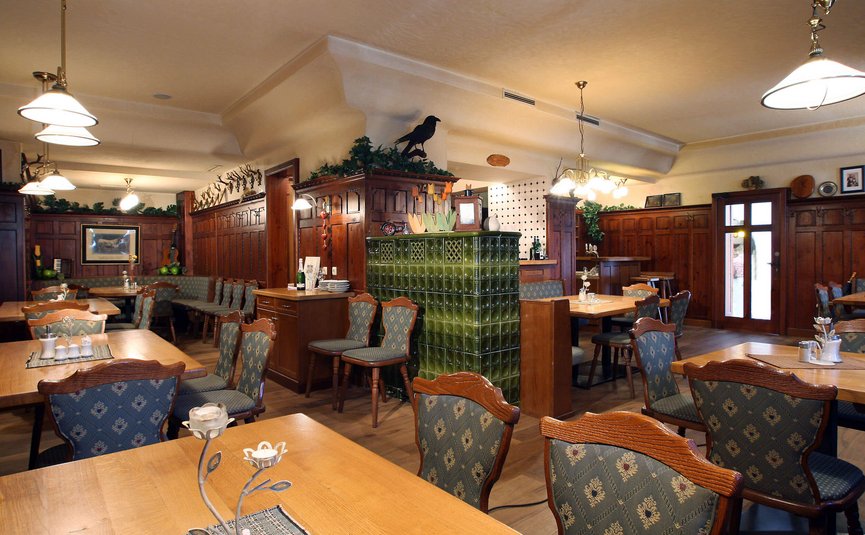 Gemütliches Restaurant mit Holzmöbeln und grünem Kachelofen