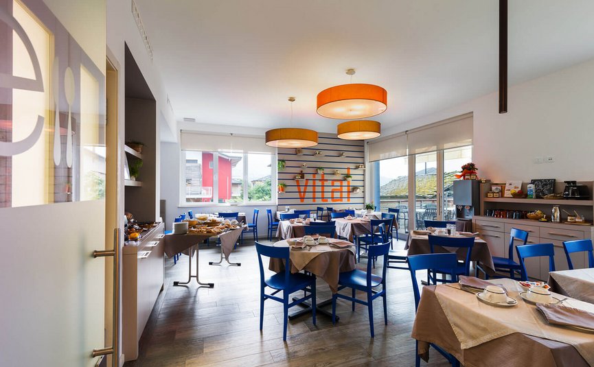 Helles Restaurant mit blauen Stühlen, gedeckten Tischen und Buffetbereich