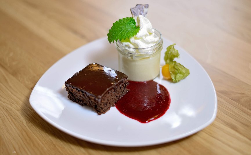 Schokoladenkuchen mit Sahne und Fruchtpüree auf weißem Teller