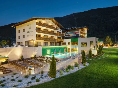 Hotel Jägerhof mit beleuchtetem Außenpool und Liegestühlen bei Nacht