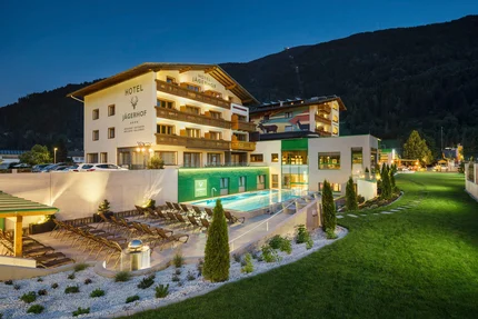 Hotel Jägerhof mit beleuchtetem Außenpool und Liegestühlen bei Nacht
