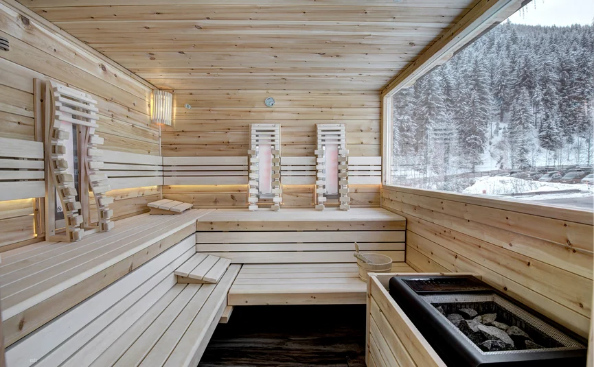 Wooden sauna interior with panoramic window showing snowy forest