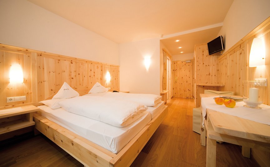 Helles Hotelzimmer mit Holzmöbeln, Doppelbett und Äpfeln auf dem Tisch
