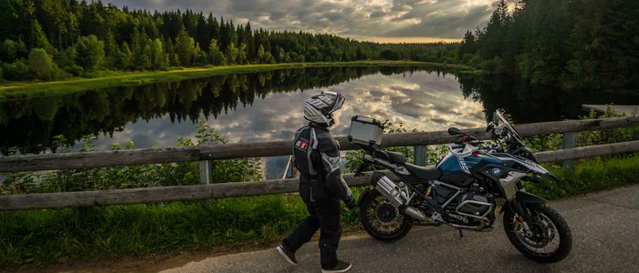 Wohlfühlhotel Rockenschaub **** © Moppetfoto.de Motorradfahrer schiebt sein Motorrad an einem Waldsee mit spiegelnder Wasseroberfläche entlang