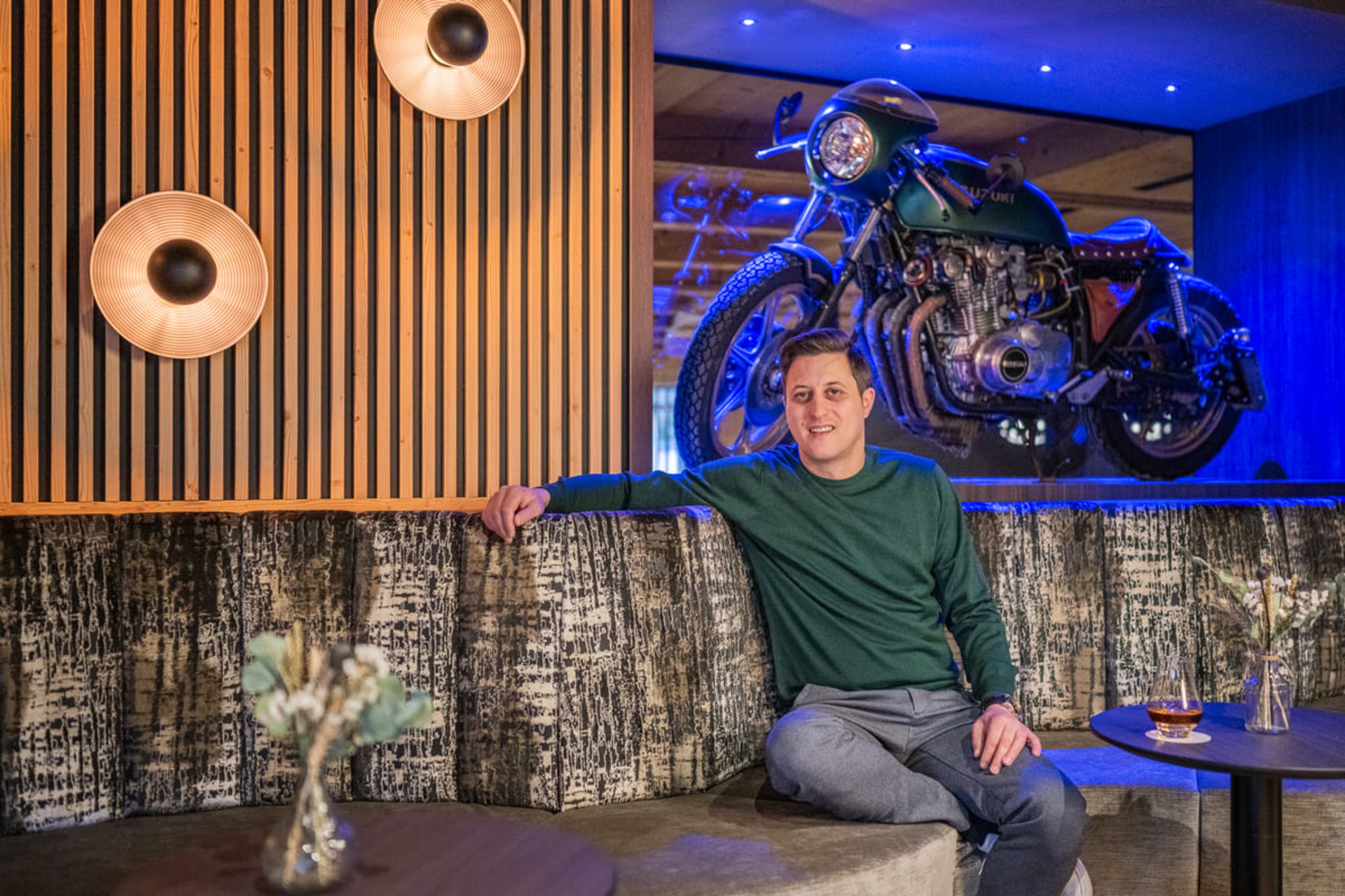 Mann sitzt in Lounge mit einer Vintage-Motorrad-Dekoration an der Wand