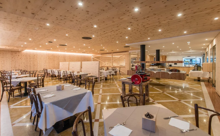 Cristallo Sport & Wellness Hotel **** © Andrea Acler Leerer Restaurantinnenraum mit Holzwänden und Tischen mit Tischdecken