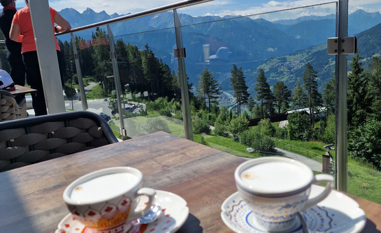 Zwei Tassen Kaffee auf Tisch mit Bergpanorama und blauem Himmel