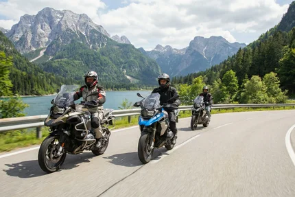 De zonnige kant van Italië Motorrijders op bergweg langs meer met bergen op de achtergrond