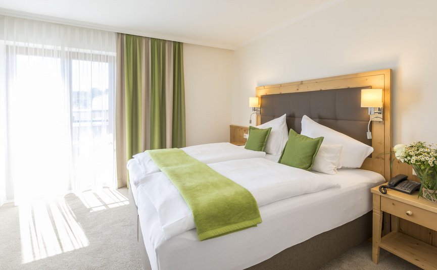 Hell eingerichtetes Hotelzimmer mit Doppelbett und grüner Dekoration