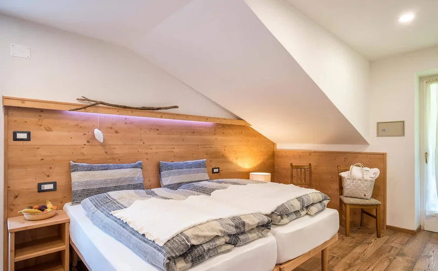 Gezellige slaapkamer met houtaccenten en tweelingbedden onder schuin plafond