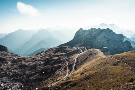 Narrow roads winding through rocky mountain range under clear sky