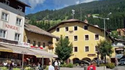 Belebter Platz mit Menschen, Restaurants und Bergen im Hintergrund