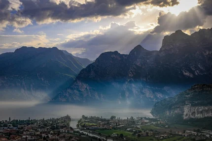 Sun rays piercing clouds over mountains and village by the lake