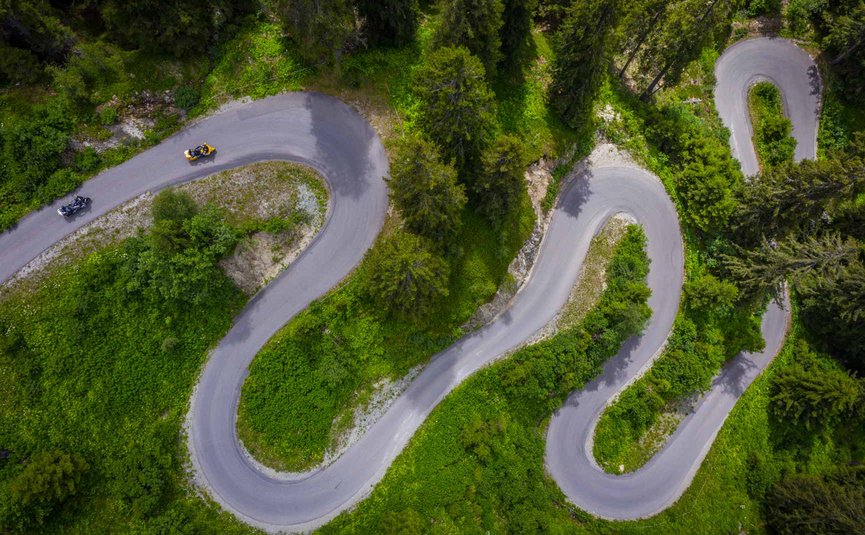 Motorradurlaub in Tirol © Moppetfoto.de Luftaufnahme einer kurvigen Bergstraße mit Motorrädern und grüner Vegetation