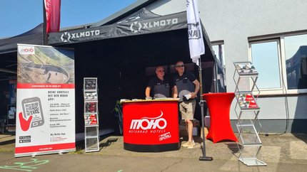 Messestand von MoHo Motorrad Hotels mit zwei Männern und Informationsmaterial