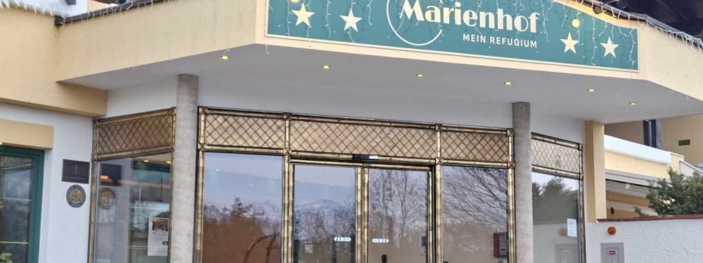 Eingang mit goldenen Glastüren und Marienhof-Schild, weihnachtlich dekoriert