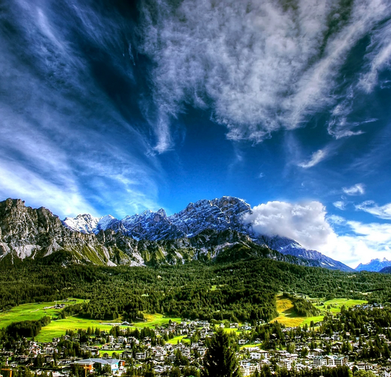 Berglandschaft mit Dorf, Wald und dramatischem Himmel