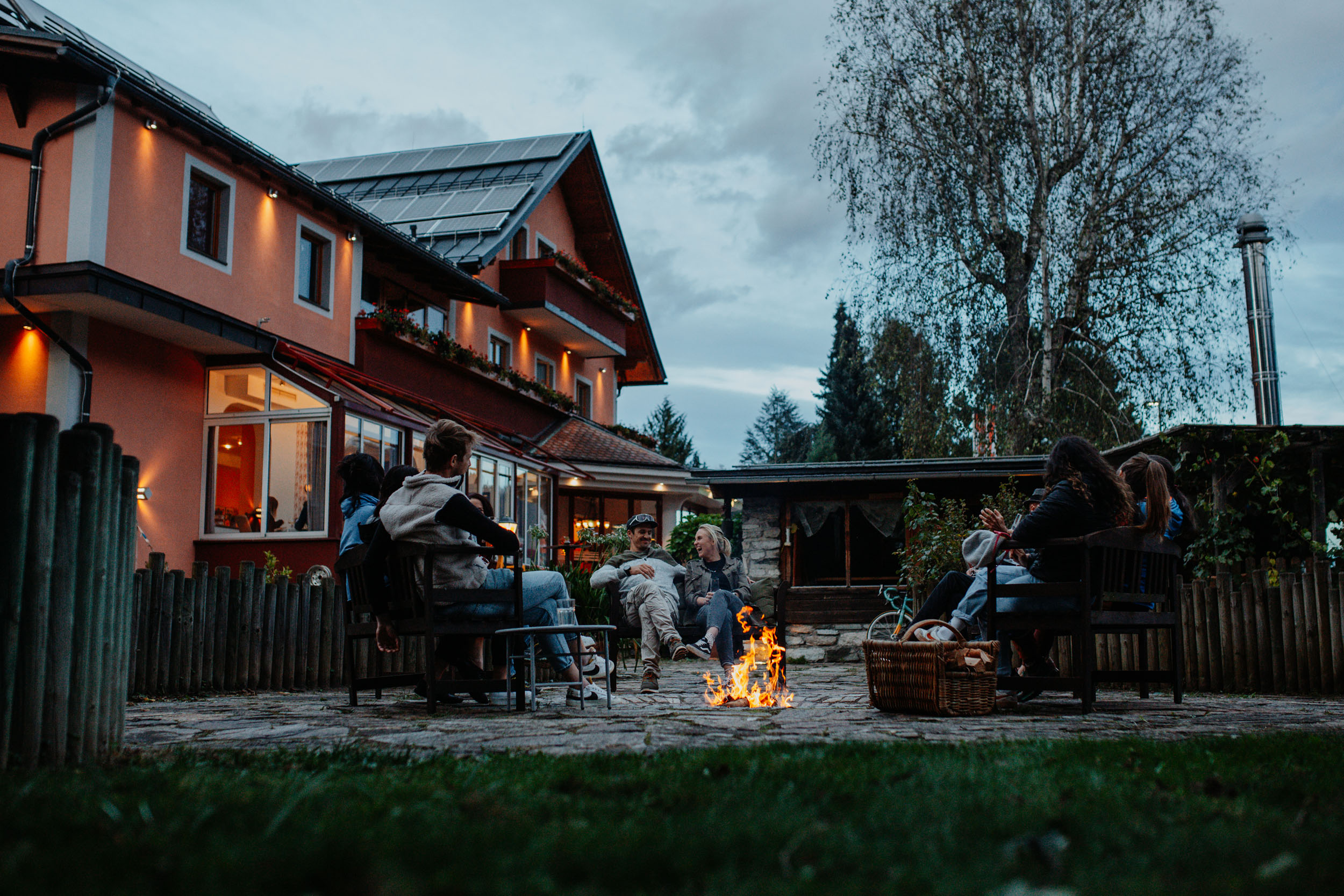 Jouw motorervaring © Niko Opetnik Groep mensen zit rond kampvuur in de tuin van een huis in de avond