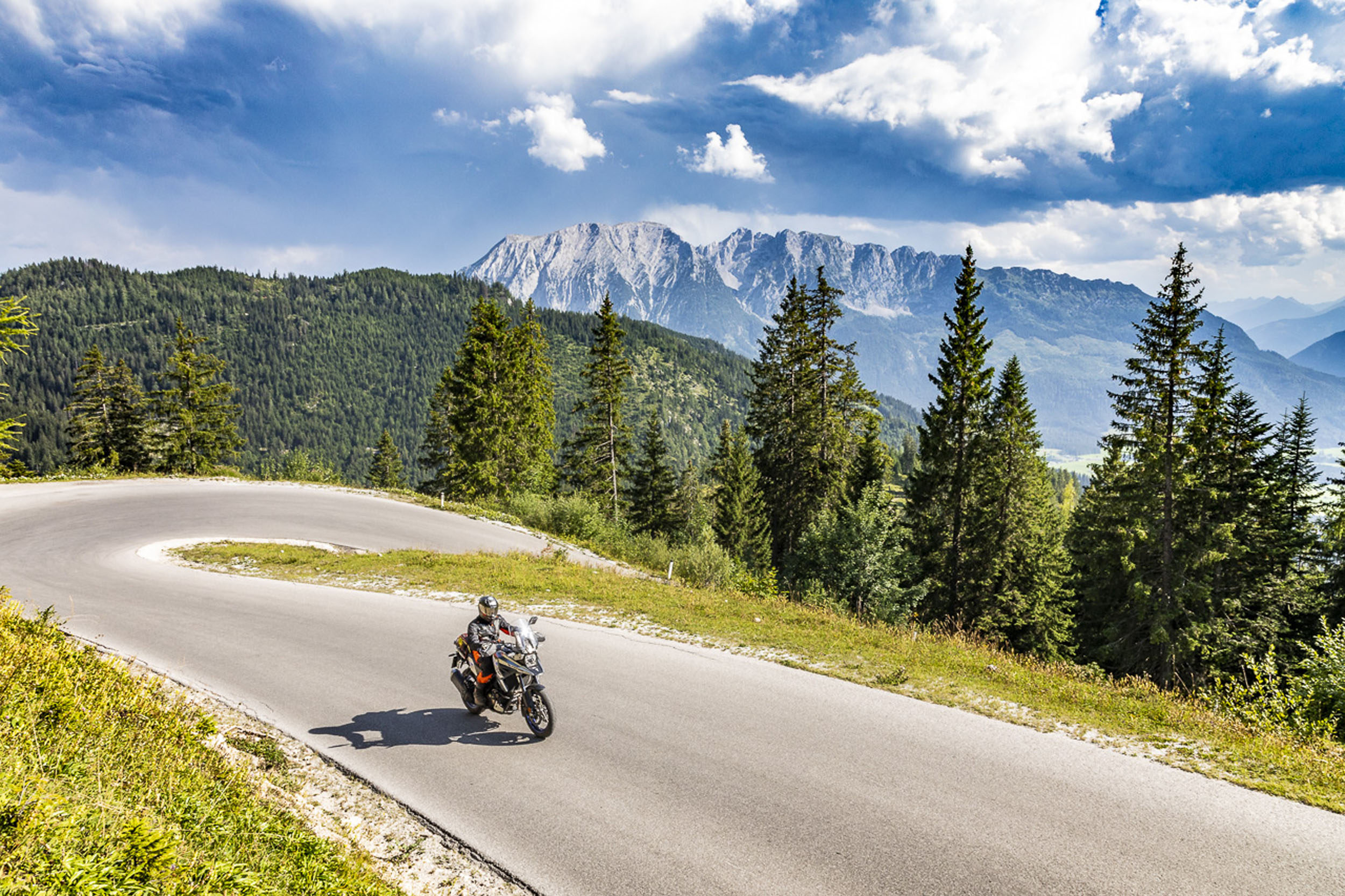 Motorbike holiday in Styria © Alexander Seger Motorcyclist on winding mountain road with pine trees and mountains behind