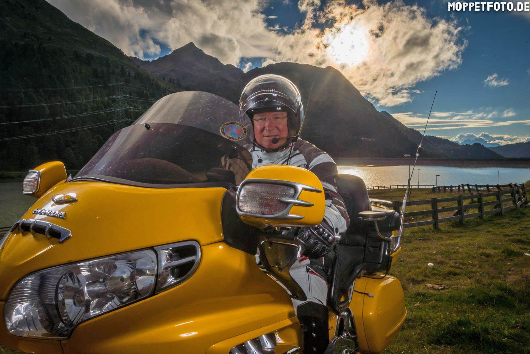 Jouw motorervaring © Moppetfoto.de Man op gele motorfiets met berglandschap bij zonsondergang