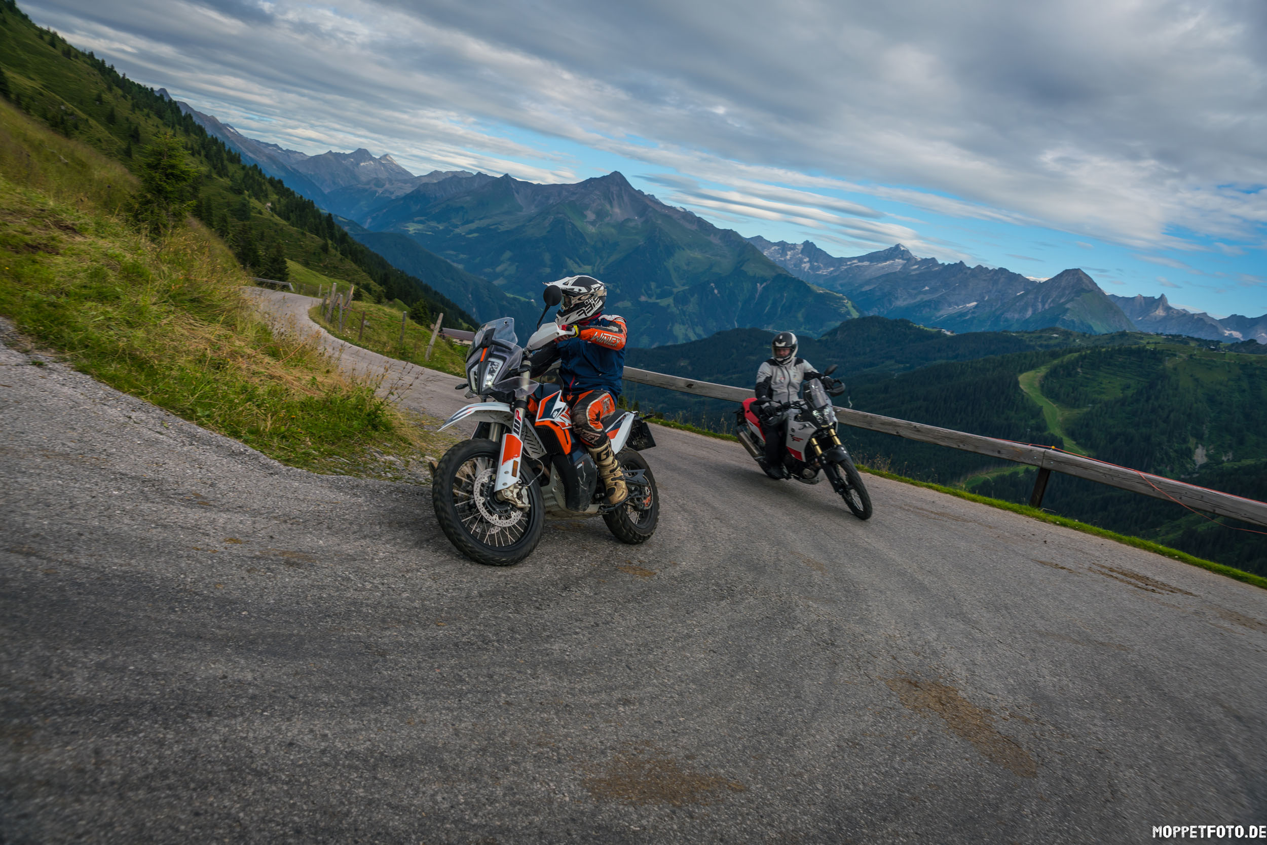 Jouw motorervaring Motorrijders op een kronkelende bergweg met Alpen op de achtergrond