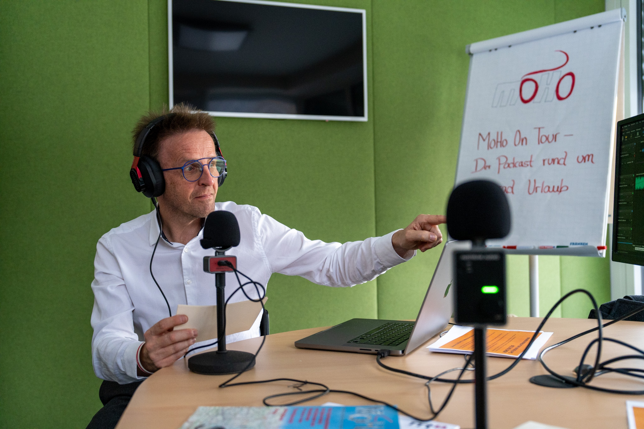 Mann mit Kopfhörern spricht in Mikrofon in einem Podcast-Studio