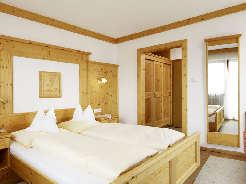 Helles Schlafzimmer mit Holzmöbeln, Doppelbett und großem Spiegel