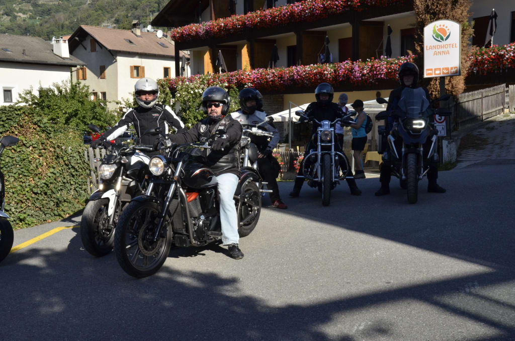 Fünf Motorradfahrer vor einem Hotel mit Blumendekoration