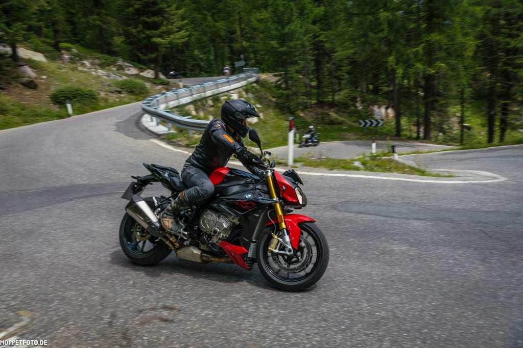 Motorradfahrer auf rotem Motorrad auf kurviger Bergstraße