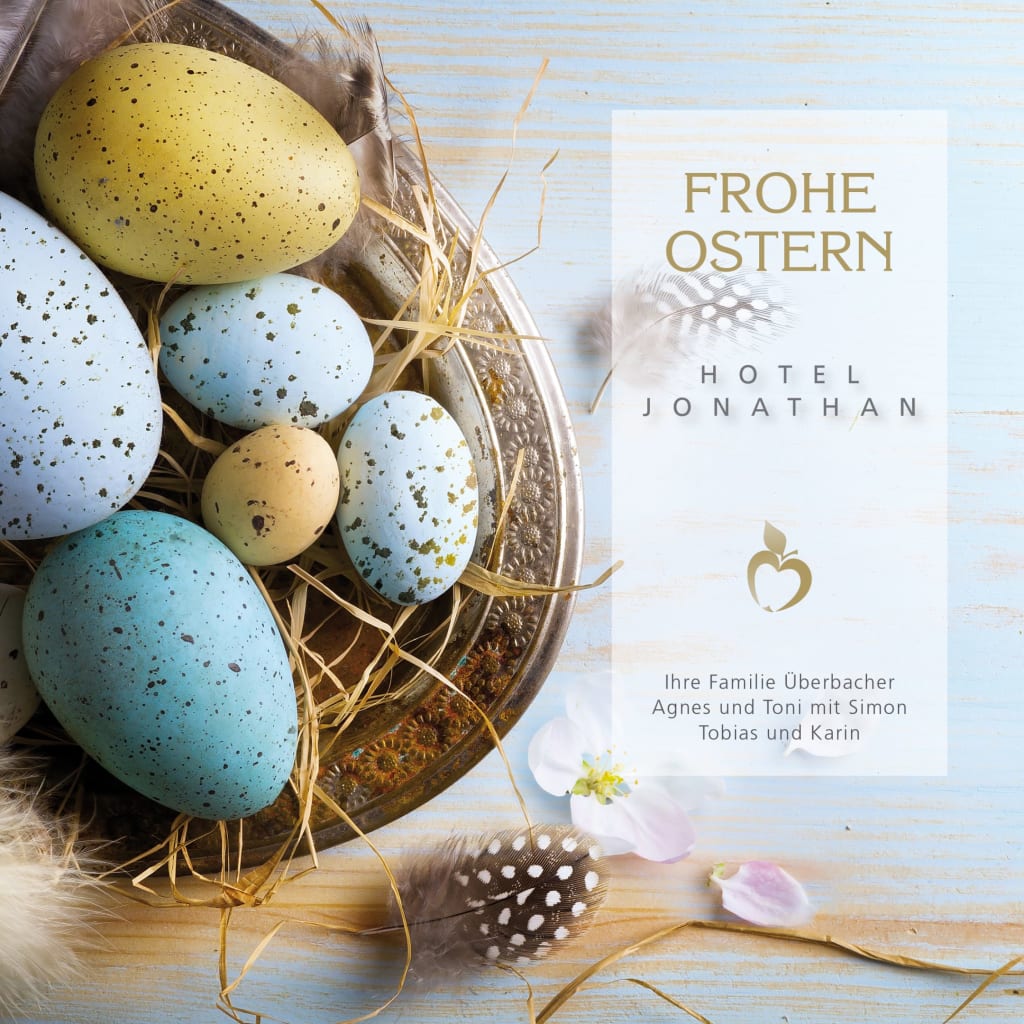 Bunte Ostereier in einer Schale mit Federn und Ostergruß