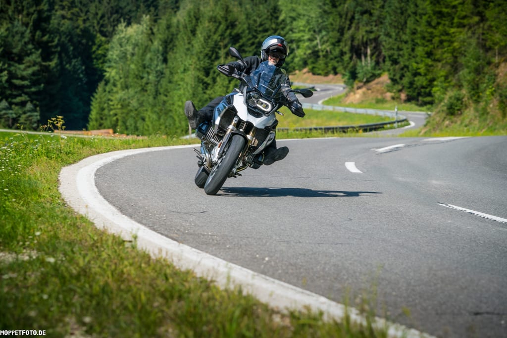 Motorradfahrer fährt eine Kurve auf einer bergigen Landstraße
