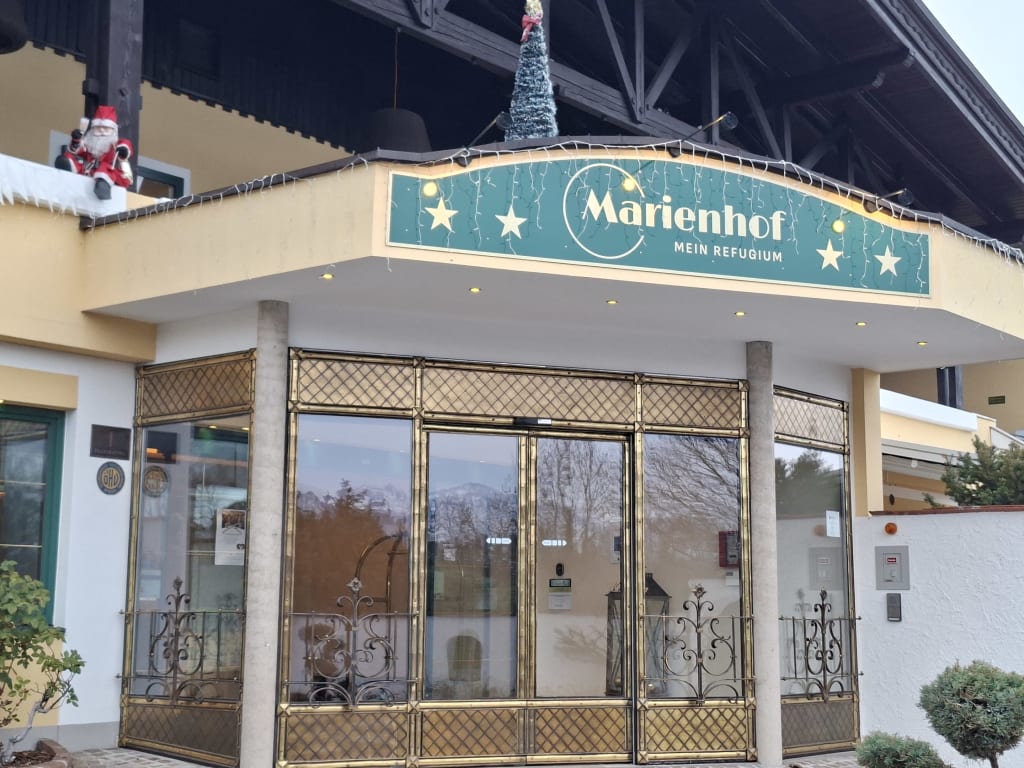 Eingang mit goldenen Glastüren und Marienhof-Schild, weihnachtlich dekoriert