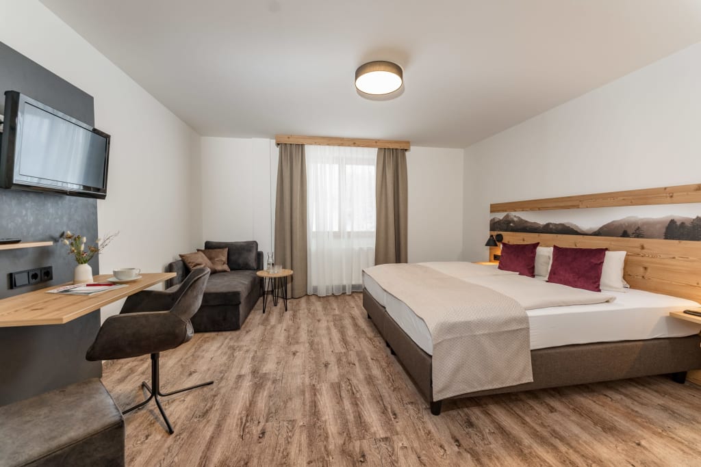 "Kurz und gut" Modern eingerichtetes Hotelzimmer mit Doppelbett, Schreibtisch und Sofa