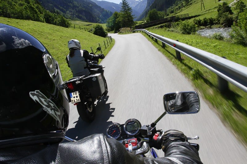 Zwei Motorradfahrer auf einer kurvenreichen Landstraße in den Bergen