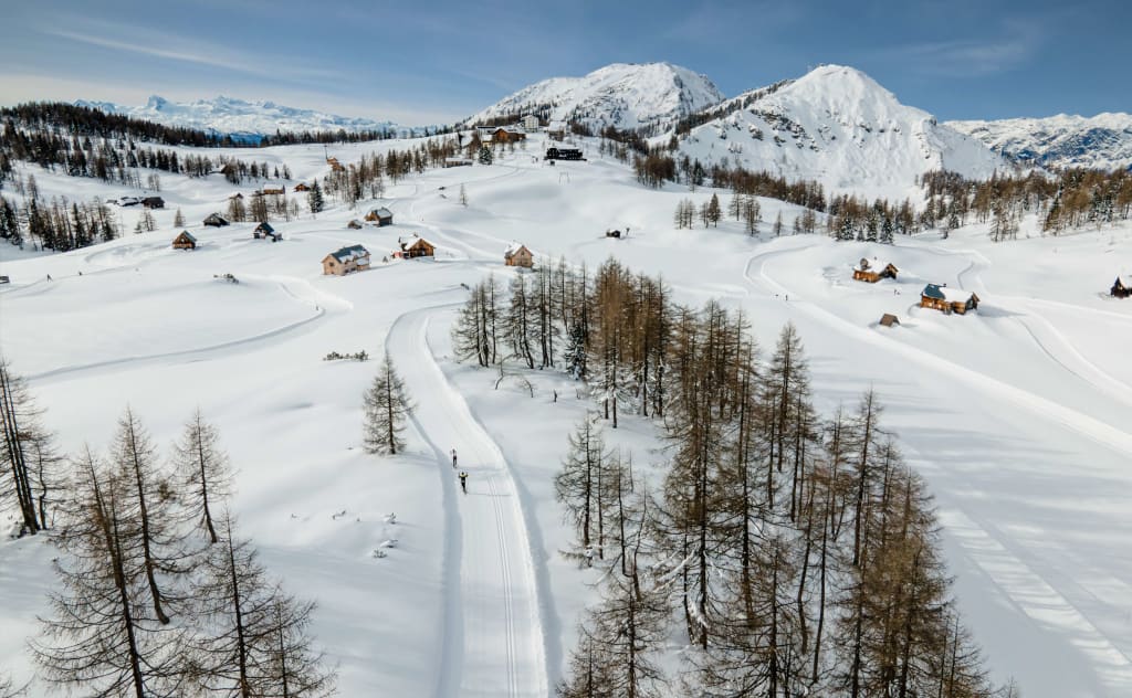 Winterzauber auf der Alm Winterlandschaft mit verschneiten Bergen, Bäumen und kleinen Häusern